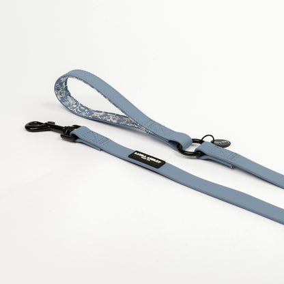 Blue dog leash with floral patterned handle laid  on a white background