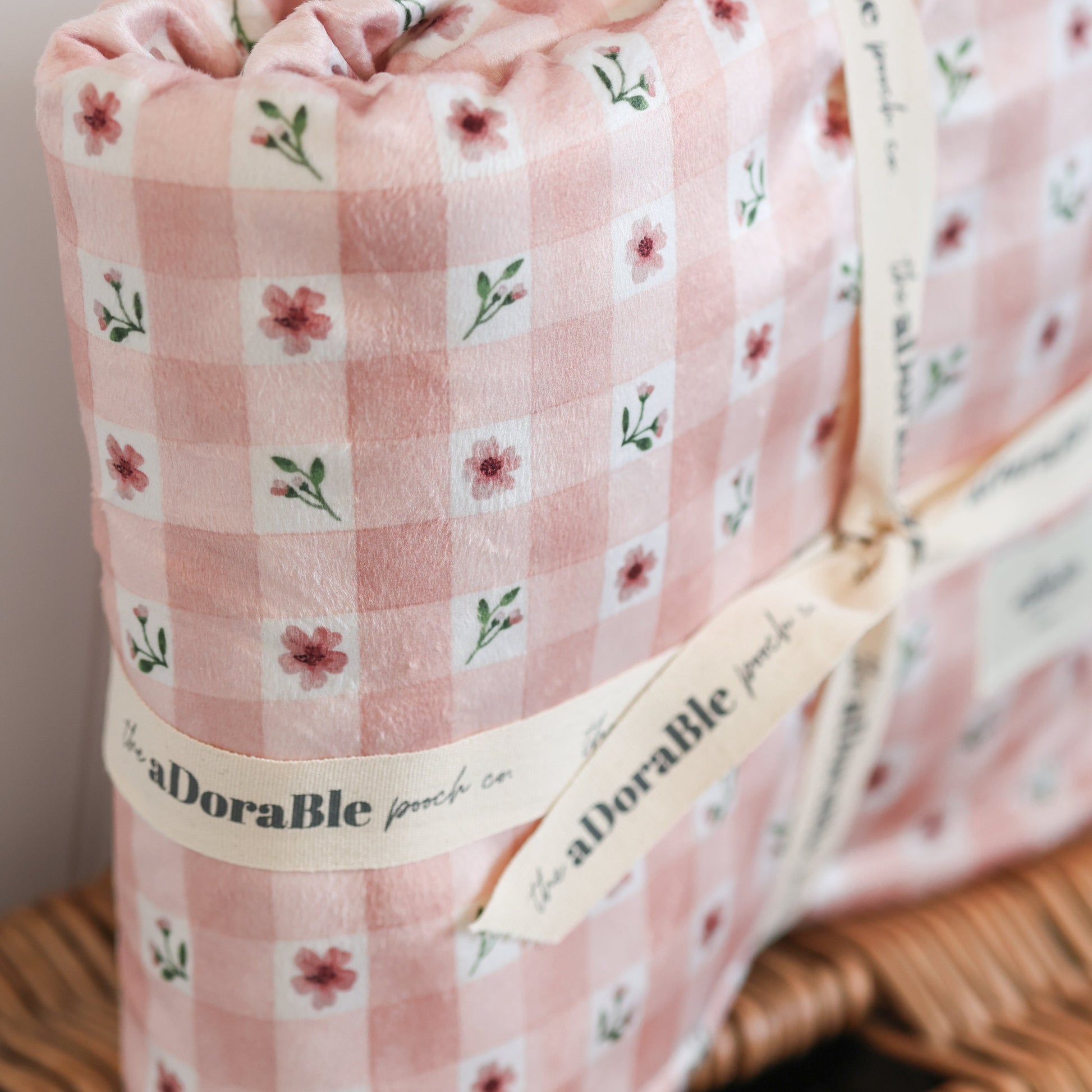 Pink checkered blanket with floral patterns on a wooden surface.