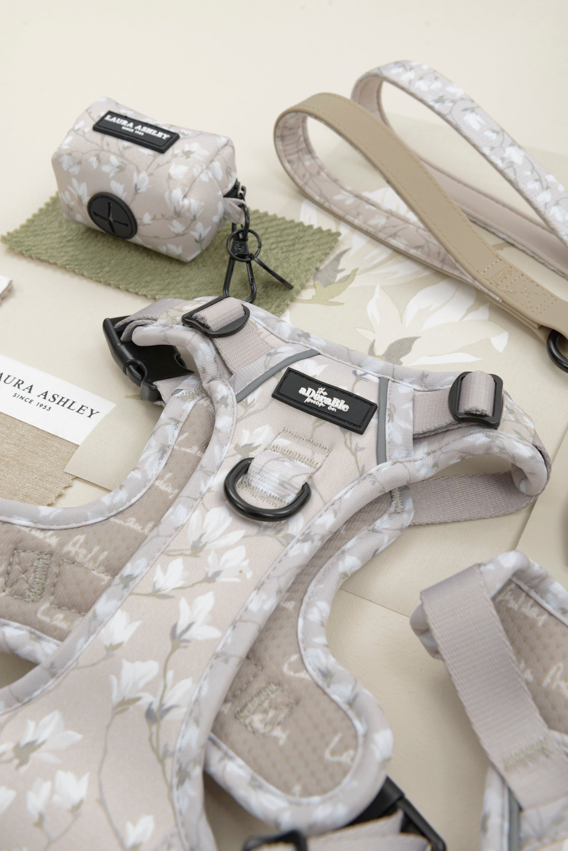 Dog waste bag dispenser in cream and white floral pattern with Laura Ashley label and hardware on a white background.